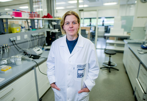 Mujer en bata de laboratorio del European XFEL de pie en medio de un laboratorio