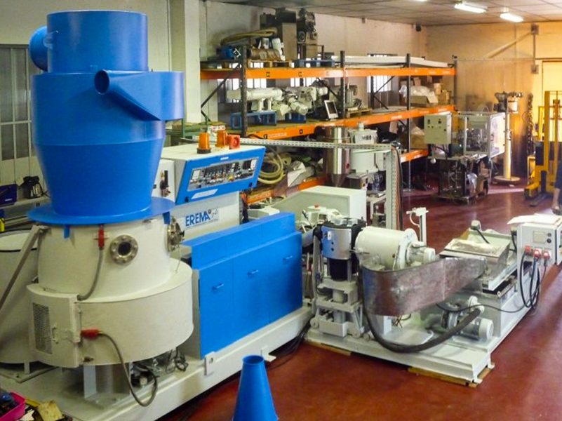 Instalaciones de producción dentro de una nave de una fábrica, con una gran máquina de reciclado de plástico.
