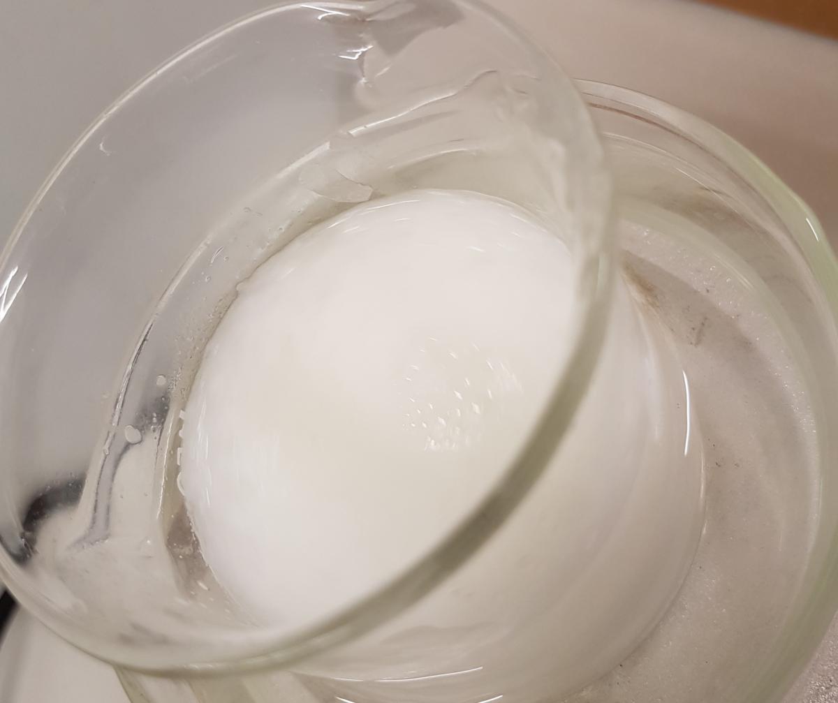 Mixing the aqueous phase solution with the oily phase solution produces the homogenous base cream.