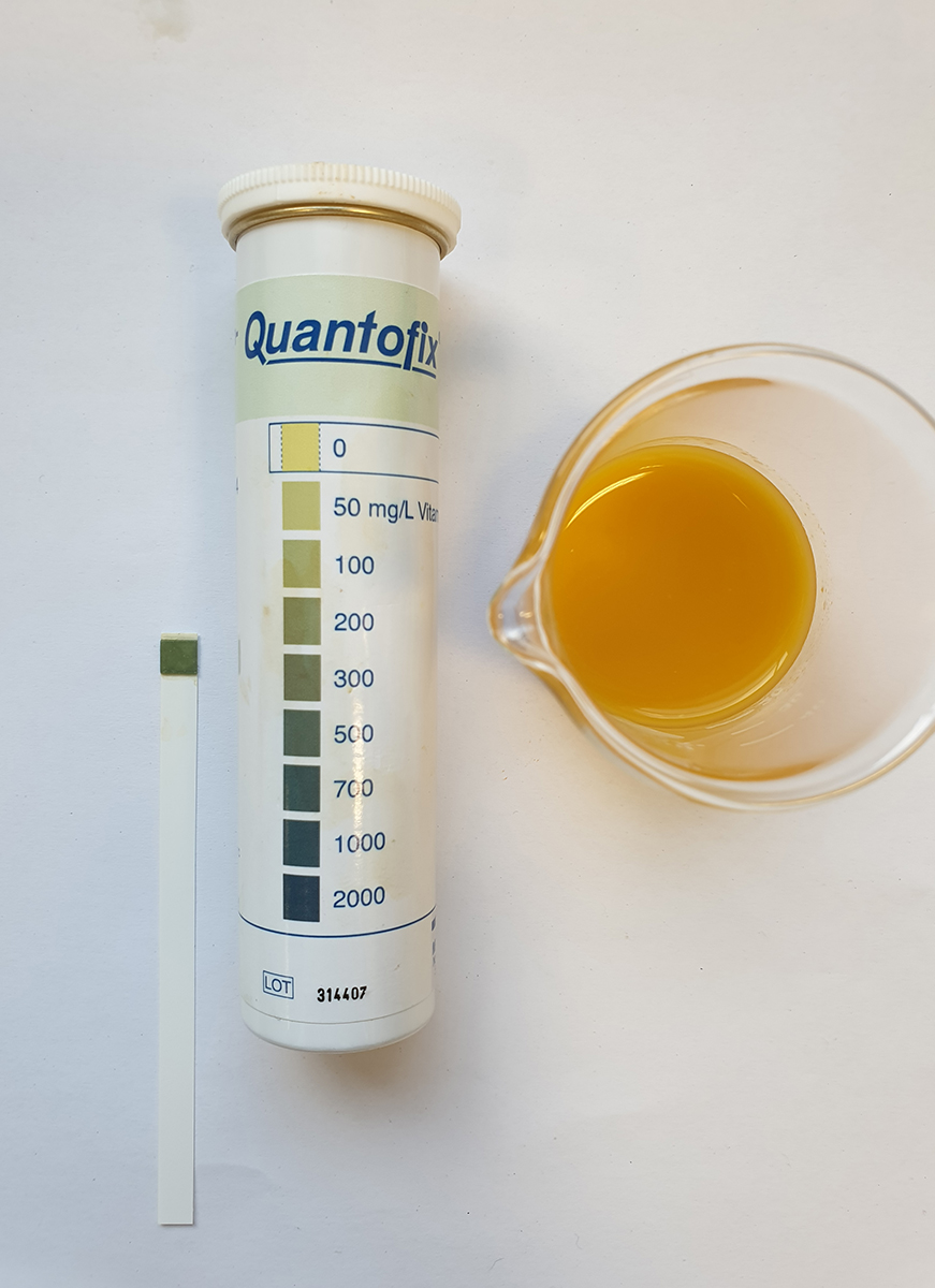 Vitamin C test strip and scale after immersion in orange juice