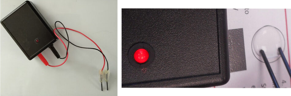 The LED of a conductivity indicator shines brightly when the electrodes touch a drop of water containing salt.