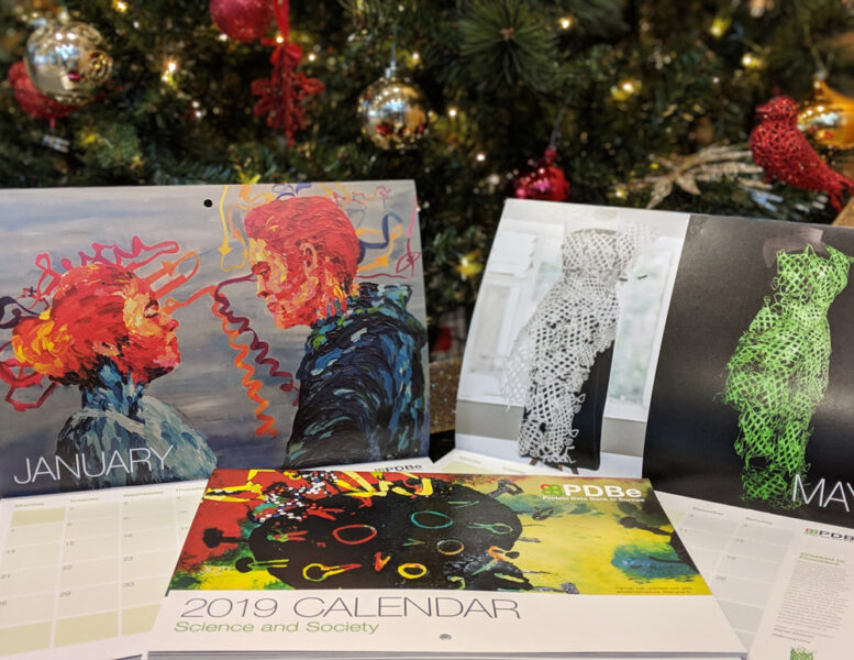 PDB Art calendars from previous years on display in front of a Christmas tree.