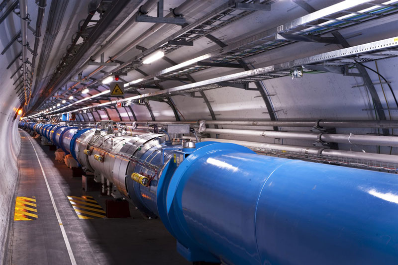 Inside the Large Hadron Collider (LHC) tunnel at CERN. The blue beam pipe runs through the tunnel as far as the camera can see.