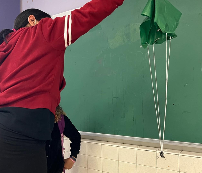 A student dropping a homemade parachute to test the air resistance.