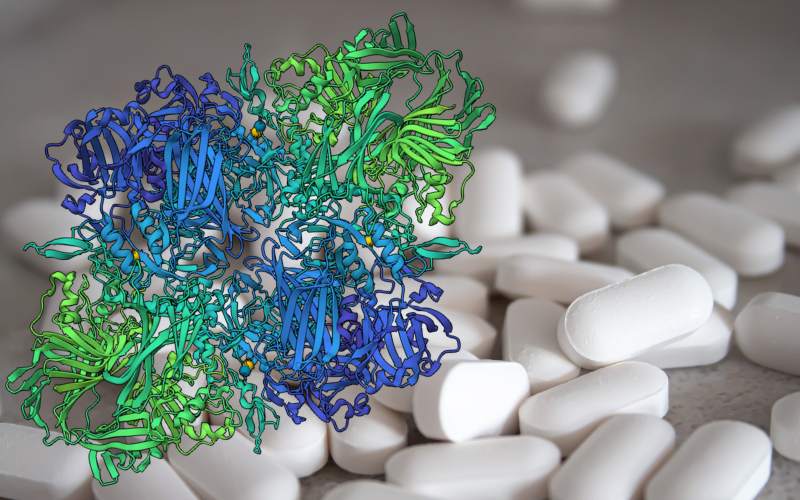 A bunch of white pills in the background with the structure of the E.coli in green and blue in the front.