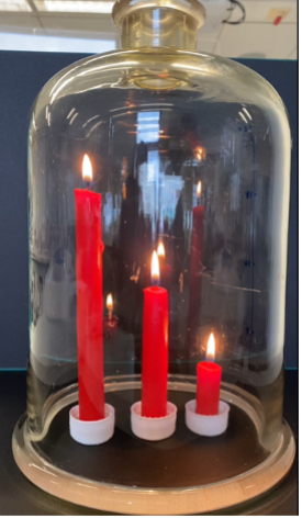 A glass cloche with three red candles inside of it.